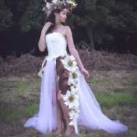 nature fairy wearing a long flowy white dress with brown hair and a crown made out of flowers